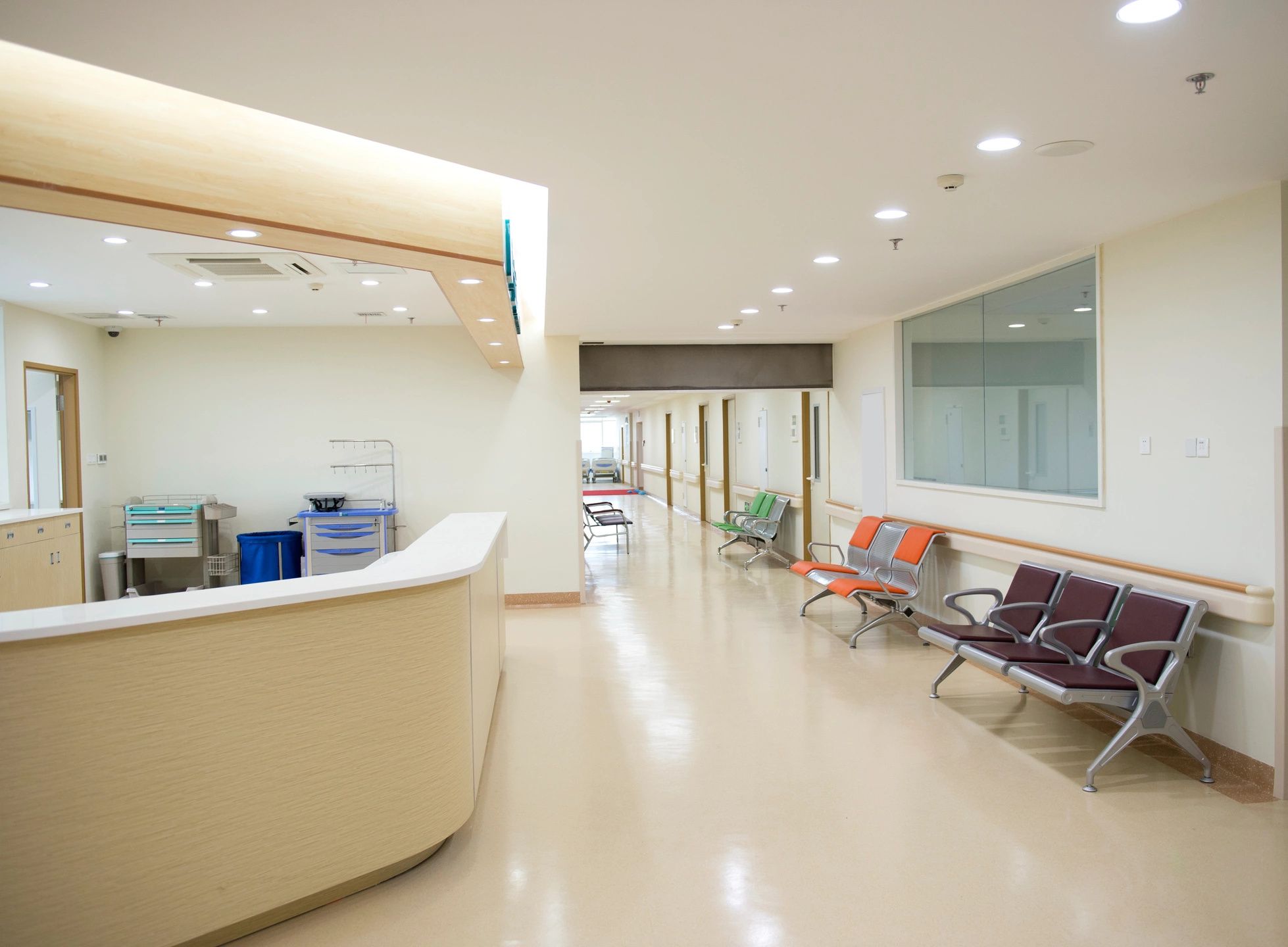 A hospital waiting room with chairs and a reception desk.