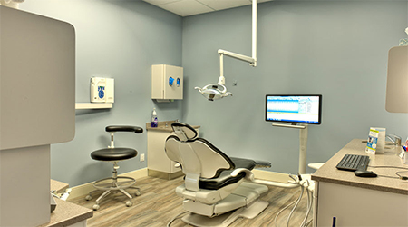 A dentist 's office with a computer and chair.
