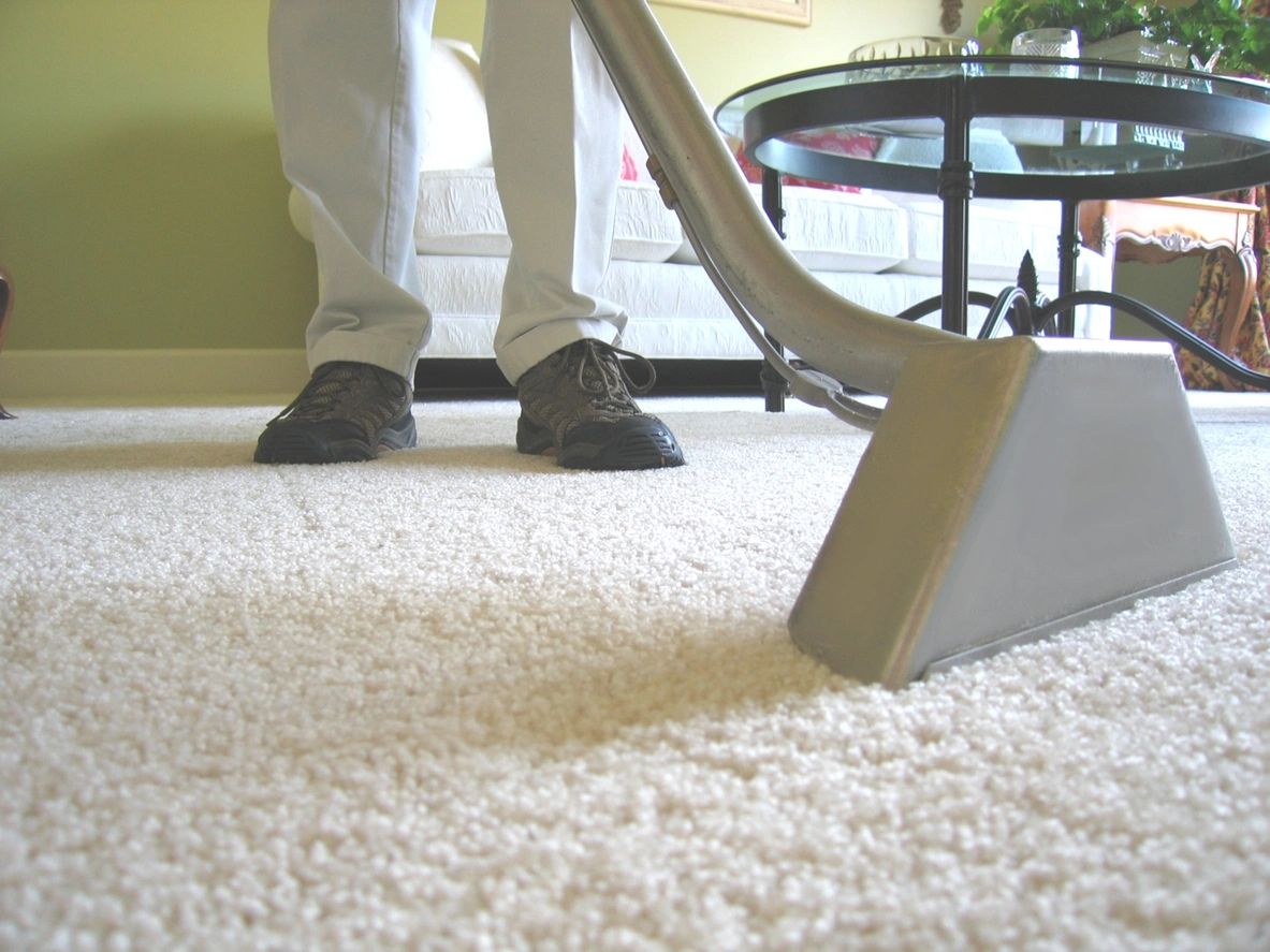 A person is using a carpet cleaner on the floor.
