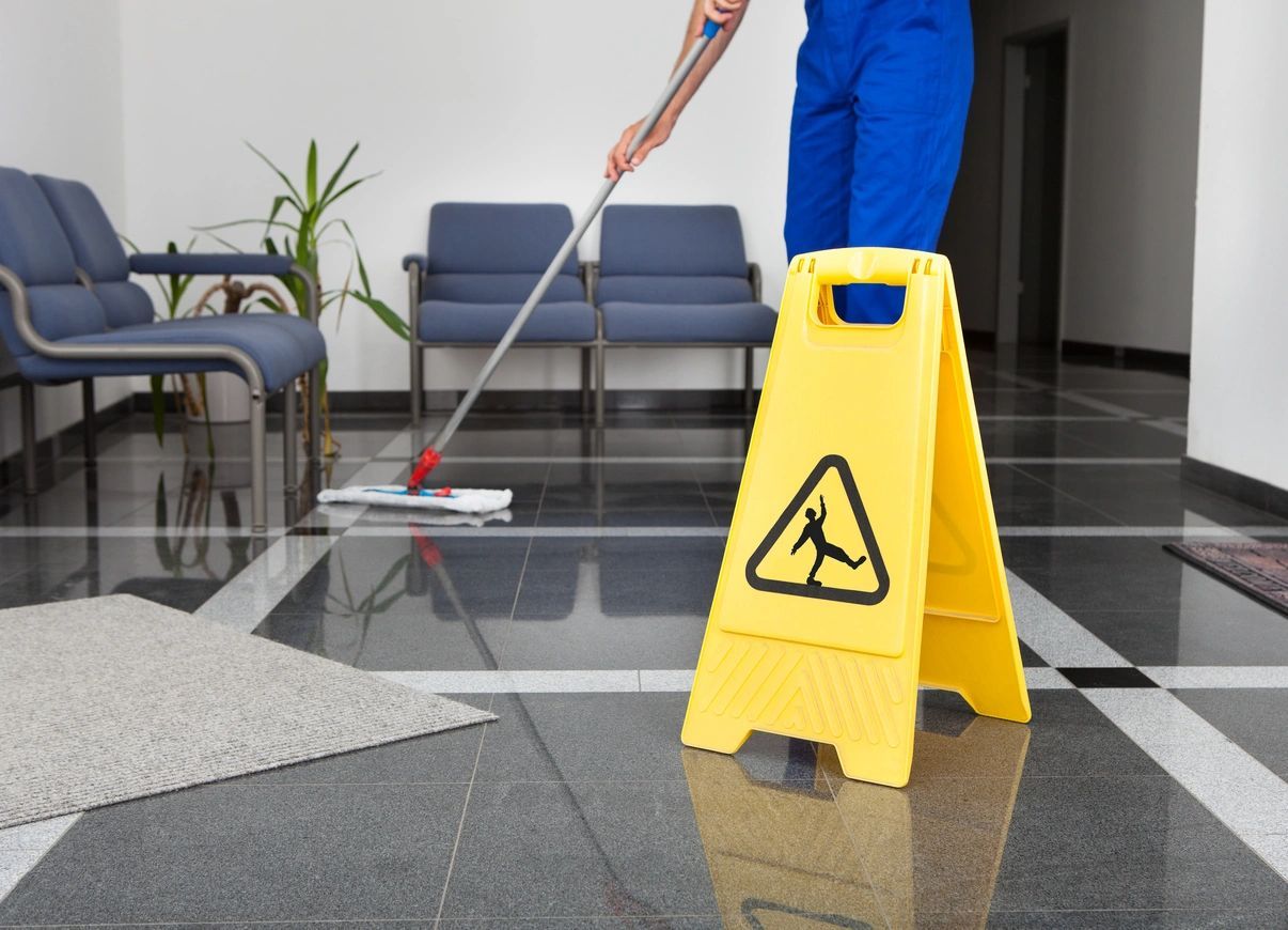 A person mopping the floor with a wet mop.