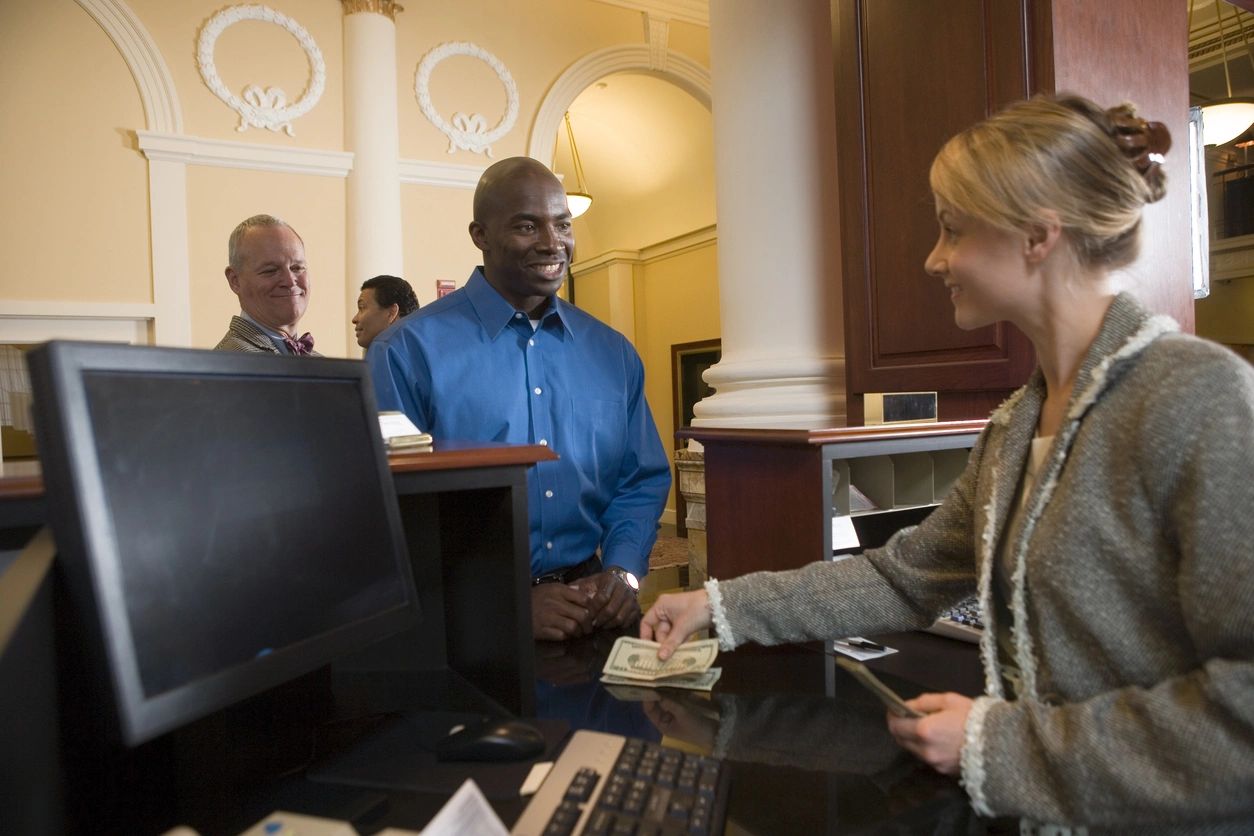 A man and woman at the counter of a hotel.